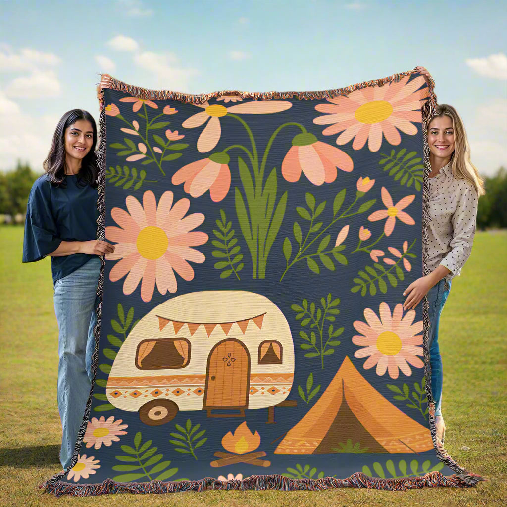 Two people holding a floral blanket with camping designs in a room.