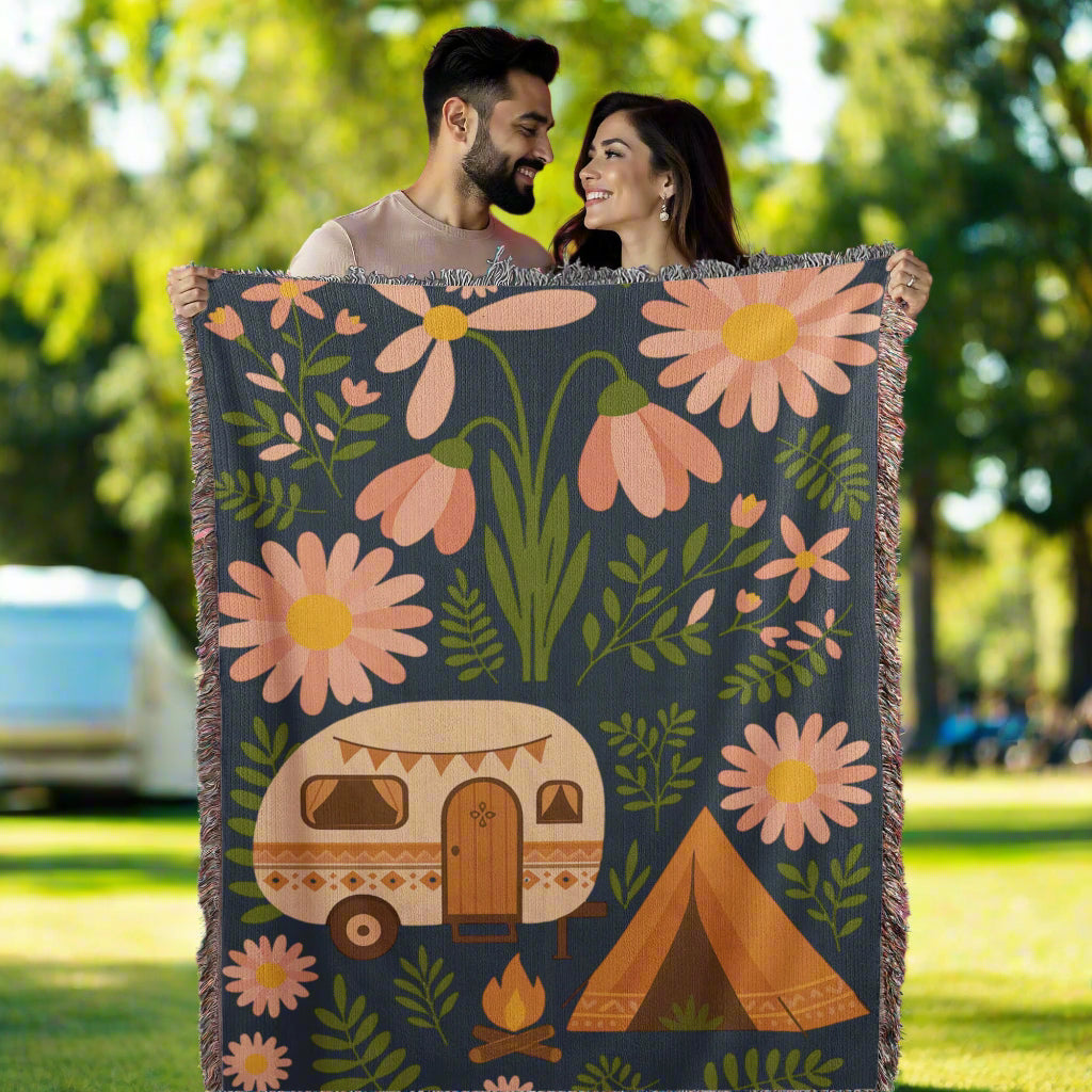 Couple holding a floral blanket with a caravan and tent design against a pink background with heart balloons.