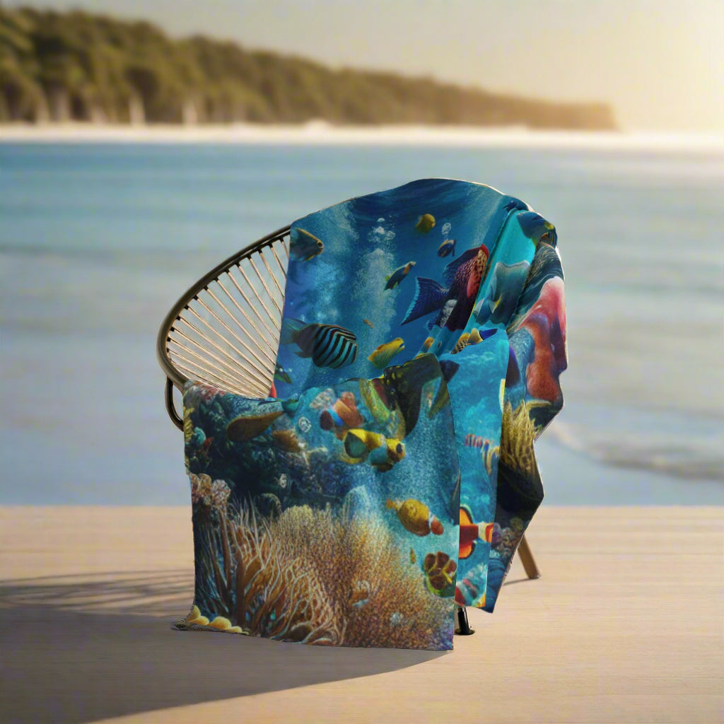 Colorful underwater-themed blanket draped over a chair in a room with light wood flooring and a plant.